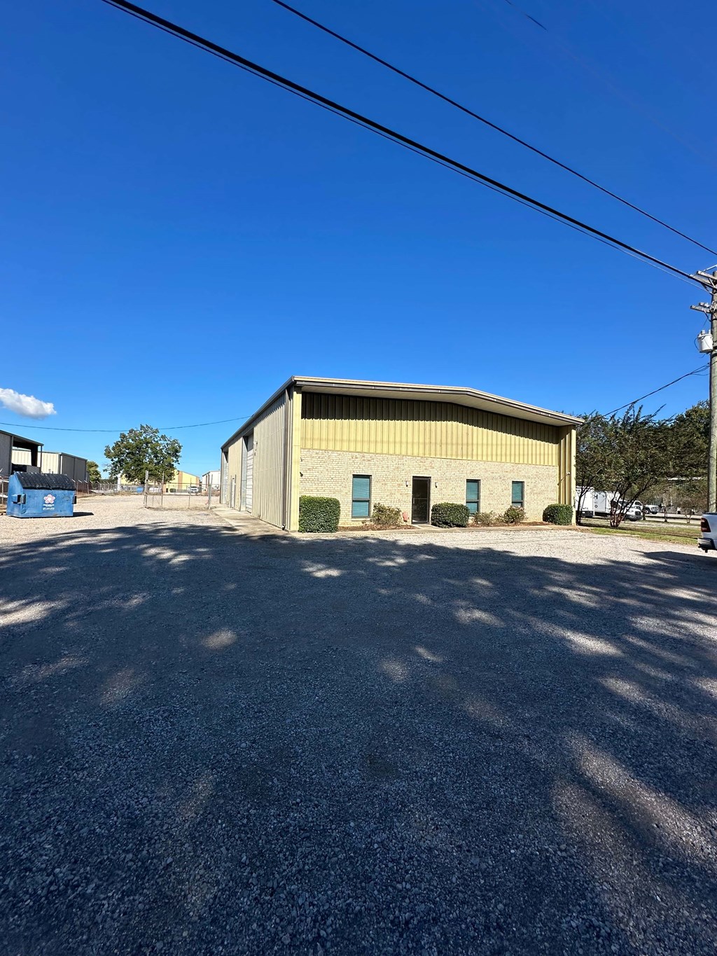 A large building with a yellowish facade is surrounded by a gravel lot.