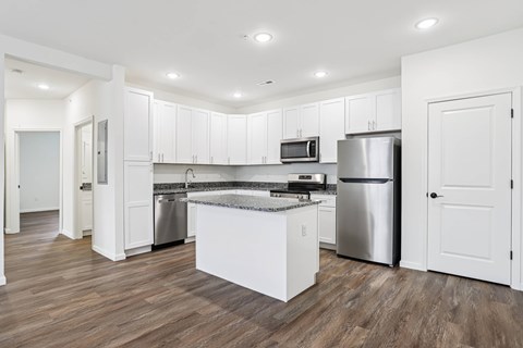A kitchen with white cabinets and a wooden floor.