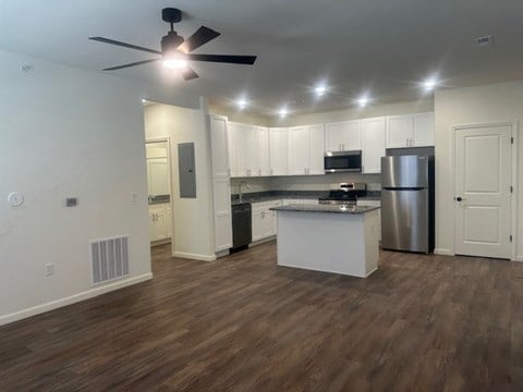 A kitchen with white cabinets and a wooden floor.