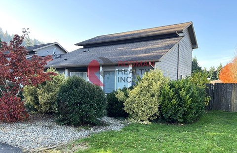 A real estate sign is on the side of a house.