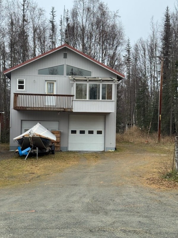 A house with a garage and a covered patio is surrounded by trees.