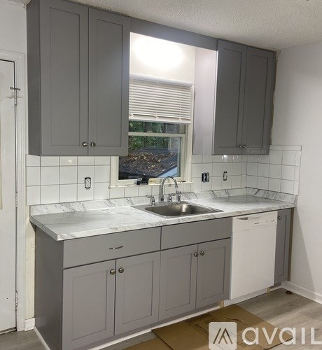 A kitchen with grey cabinets and a white sink.