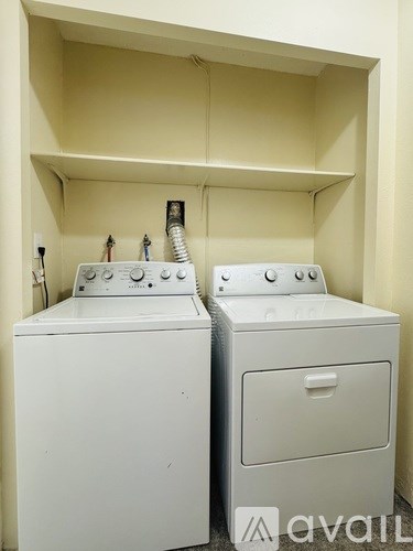 Two white front loading washing machines in a small laundry room.