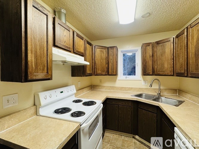 A kitchen with a white stove top oven and wooden cabinets.