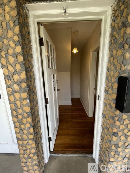 A hallway with a stone patterned wallpaper and a wooden floor.