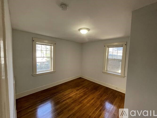 A room with wooden floors and two windows.