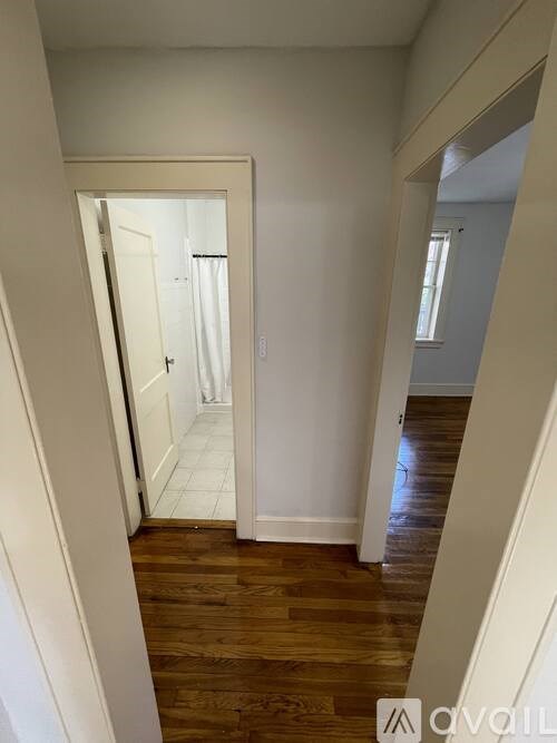 A hallway with a wooden floor and white walls.