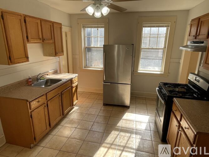 A kitchen with wooden cabinets and a stainless steel refrigerator.