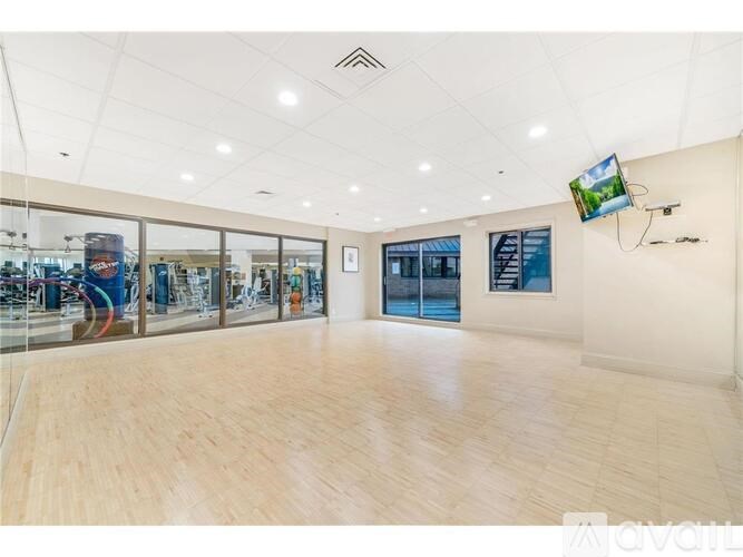 A spacious room with wooden flooring and a television mounted on the wall.