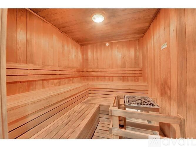 A wooden sauna with benches and a light on the ceiling.