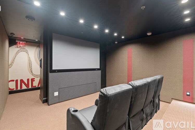 A cinema room with a row of seats and a screen.
