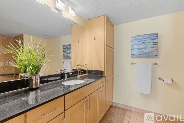 A bathroom with a black granite countertop and wooden cabinets.