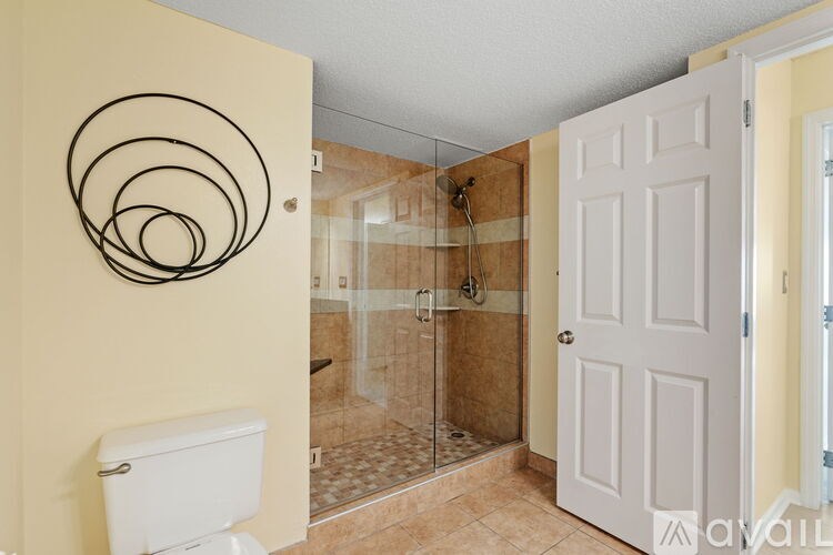 A bathroom with a toilet, a glass shower stall, and a white door.