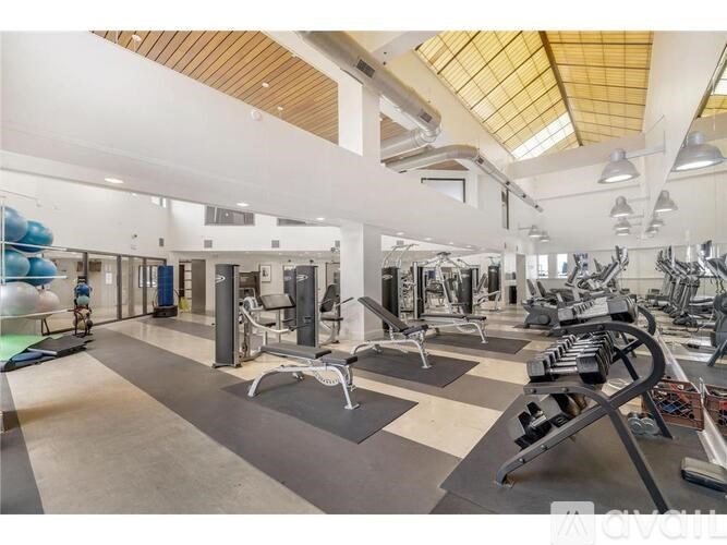 A spacious gym with a variety of equipment and a high ceiling.