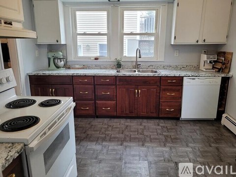 A kitchen with a white stove top oven and a white microwave above a counter with a sink.