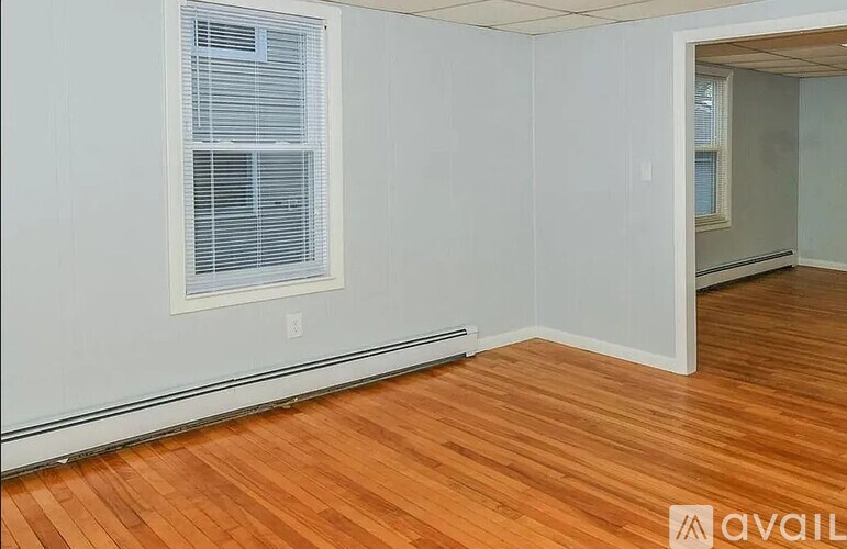 A room with wooden flooring and a window with blinds.