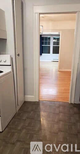 A kitchen with a white oven and a wooden floor leading to a hallway.