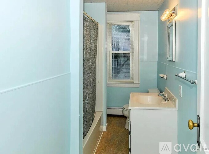 A small bathroom with a toilet, sink, and shower.