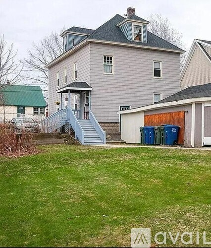 A house with a green roof and a grey exterior with a white door and windows.