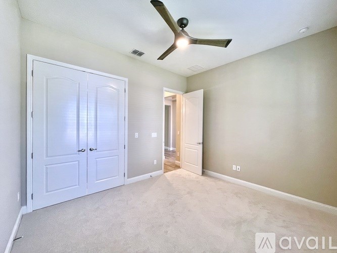 A room with a ceiling fan and two doors.