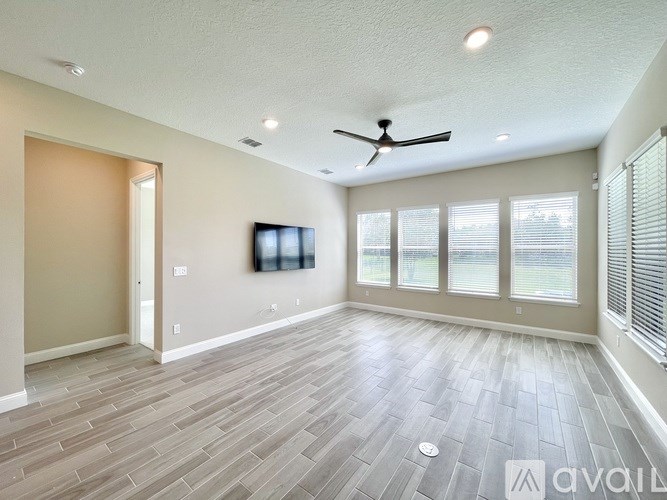 A spacious room with a ceiling fan and a flat screen TV mounted on the wall.
