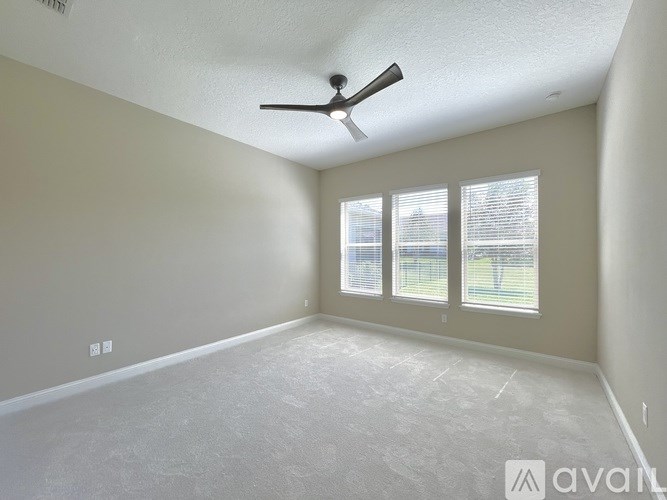 A room with a ceiling fan and two windows.