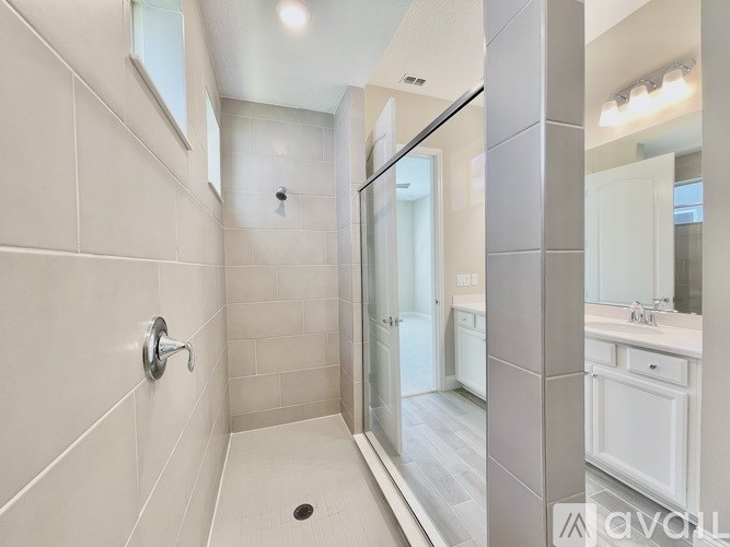 A bathroom with a white tile shower and a white sink.