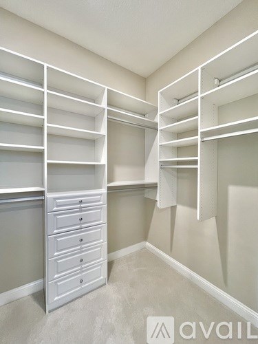 A white shelving unit with drawers is in a room with white walls.