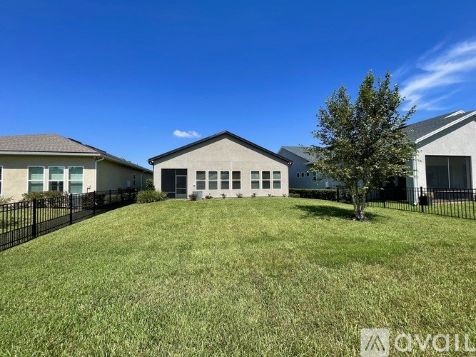 A large, well-maintained lawn in front of a two-story house with a black fence.