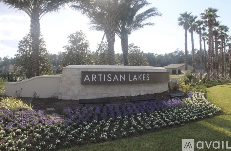 A sign that says Artisan Lakes in front of some trees.