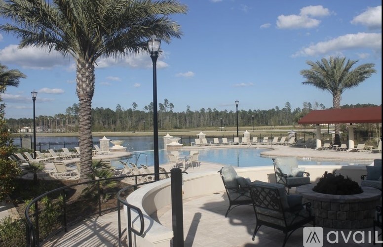 A pool area with chairs and palm trees.