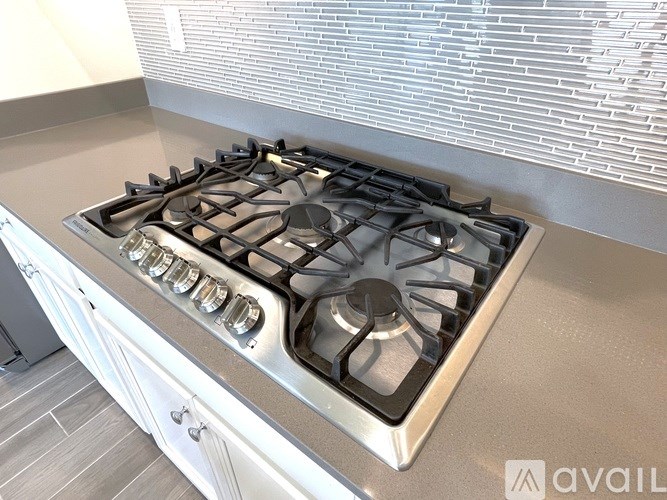 A modern stainless steel gas stove with four burners and a back control panel.