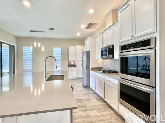 A modern kitchen with white cabinets and stainless steel appliances.