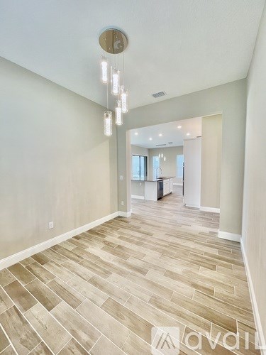 A long, narrow hallway with wood flooring and a light fixture hanging from the ceiling.