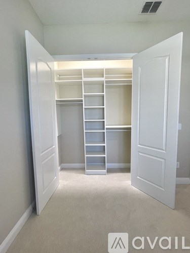 A white closet with shelves and drawers is open to a hallway.