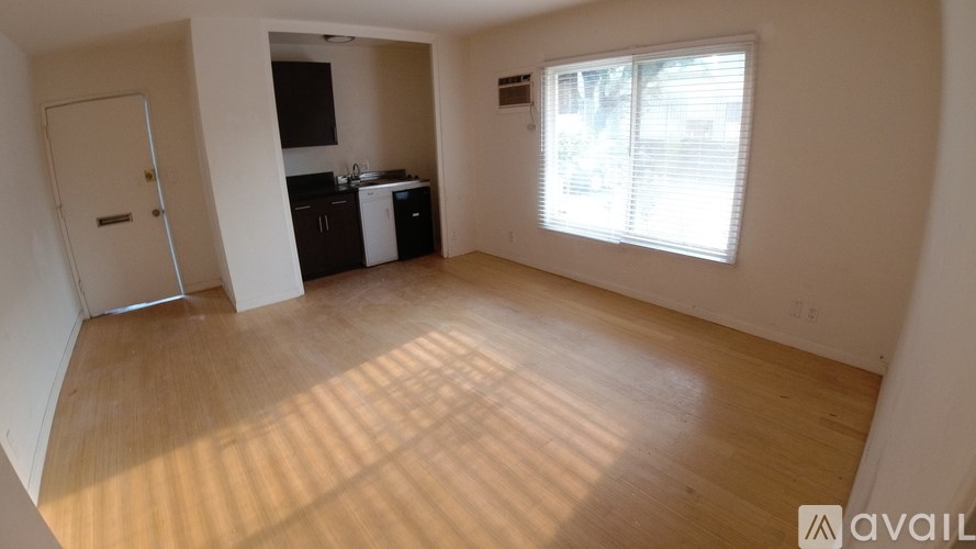 A room with wooden flooring and a window letting in sunlight.