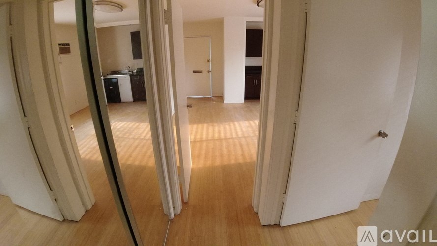 A room with wooden floors and white walls, with a door on the right side.