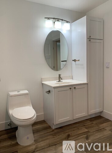 A bathroom with a toilet, sink, and mirror.