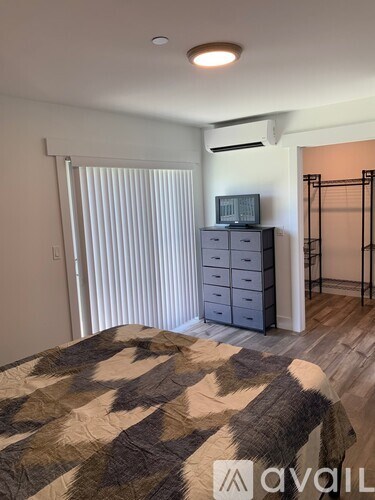 A bedroom with a bed, a dresser, and a television.