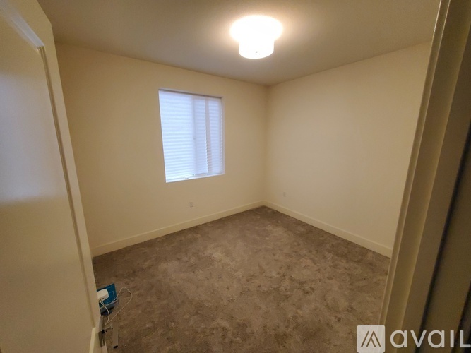 A small, empty room with a window and a carpeted floor.