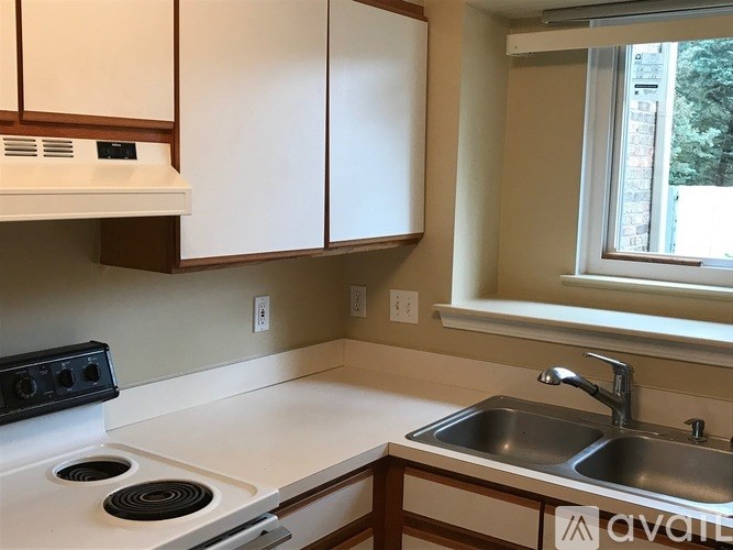 A kitchen with a white stove top oven and a stainless steel sink.