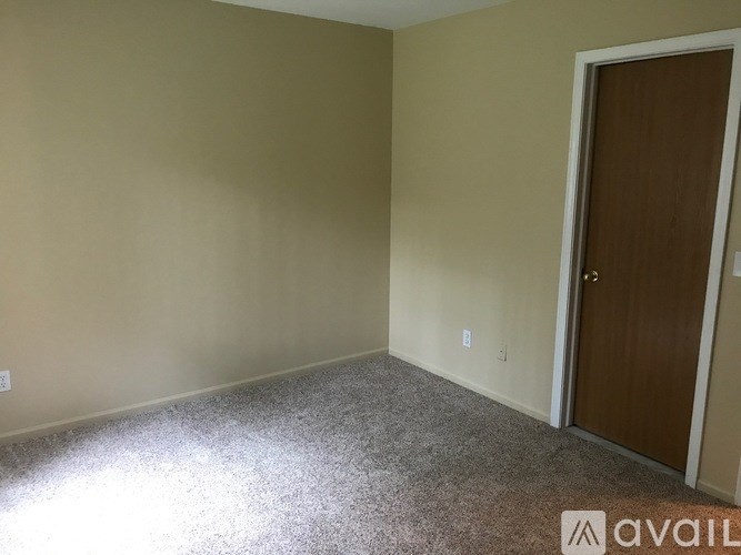 A room with a carpeted floor and a door on the right side.