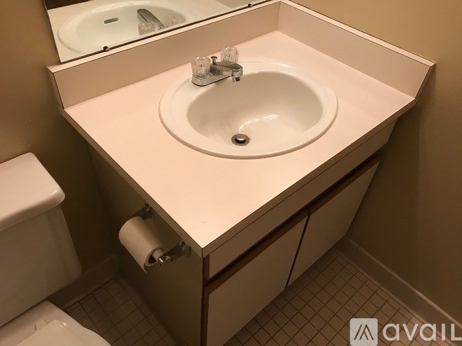 A white sink in a bathroom with a toilet and a mirror.