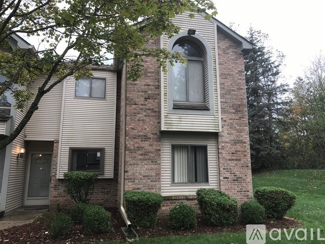 A house with a brick wall and a window with a curtain.