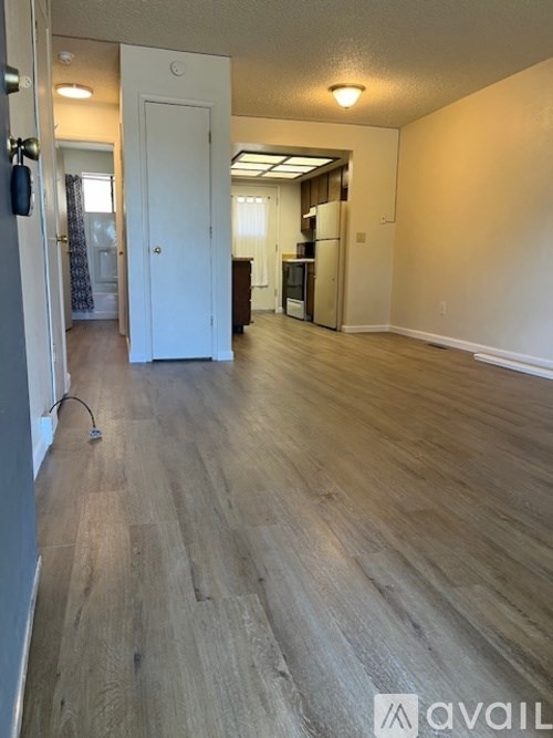 A spacious room with wooden flooring and a white door in the background.