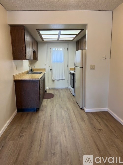 A kitchen with wooden floors and a refrigerator.