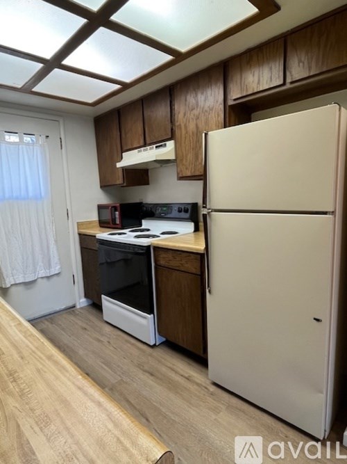 A kitchen with a white refrigerator, wooden cabinets, and a stove top oven.