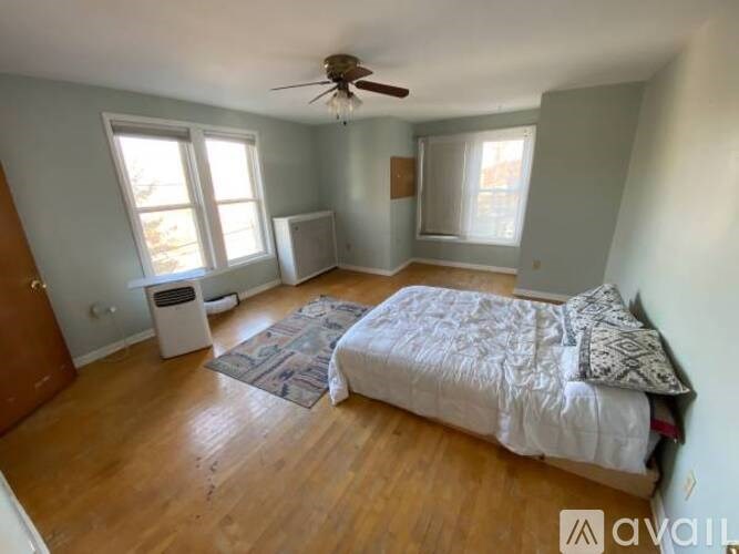 A bedroom with a bed, a trash can, and a ceiling fan.