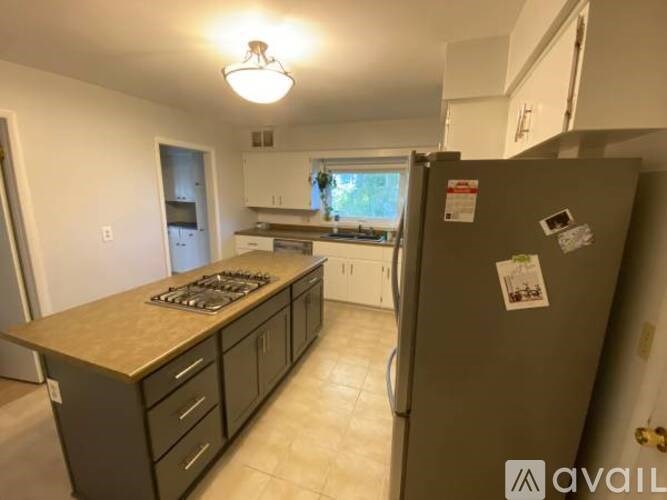A kitchen with a refrigerator, stove, and cabinets.