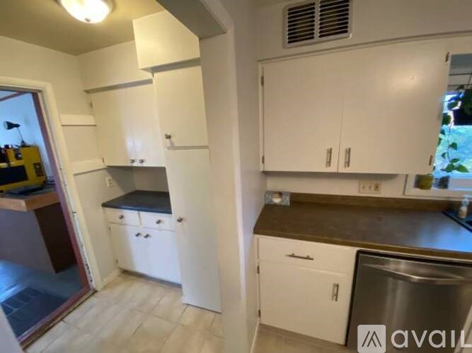A kitchen with white cabinets and a stainless steel dishwasher.